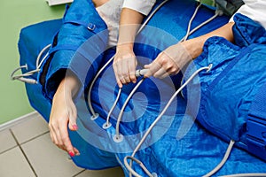 Woman in pressotherapy suit lying down having pressure therapy