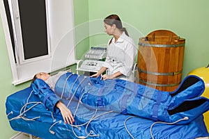 Woman in pressotherapy suit lying down having pressure therapy