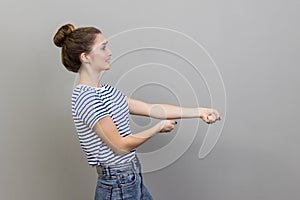 Woman pretending to pull invisible rope, concept of hard working, striving, efforts to achievements.