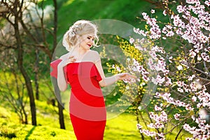 Woman or pretty girl, cute model, with long, blonde hair posing at blossoming tree with flowers in spring garden on