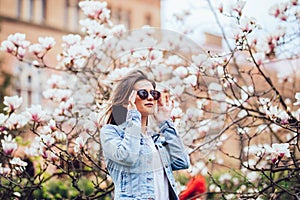 Woman or pretty girl posing at blossoming tree with magnolia flowers in spring garden on sunny day