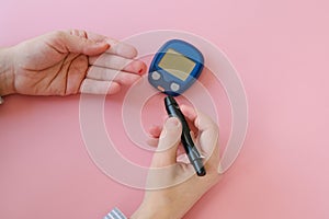 Woman pricks her finger with a lancelet to measure blood glucose levels. Diabetes, gestational diabetes mellitus concept.