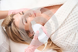 Woman on the procedure of ultrasonic facial cleansing