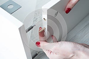 A woman inserts wooden pins into the sidewall of the furniture w