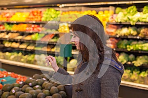 Woman in the produce section of a grocery store.