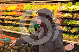 Woman in the produce section of a grocery store.