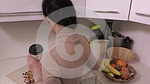 Woman with professional camera relaxing and and drinking coffee in kitchen