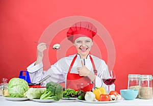 Woman professional chef hold spoon with raw mushroom. Dieting concept. Girl wear hat and apron try mushroom taste