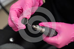 Woman on professional pedicure procedure by abrasive disc machine in beauty salon.