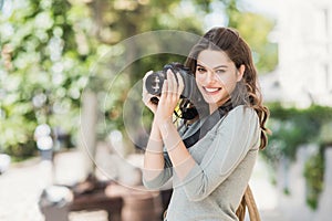 Woman professional photographer with dslr camera outdoors portrait.  Pretty young girl in the city taking images with photo camera