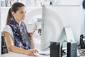 Woman professional is using a computer drinking a beverage