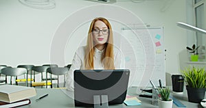 Woman professor sitting at table and lecturing online at class. Female English teacher in glasses speaking on tabletPC photo