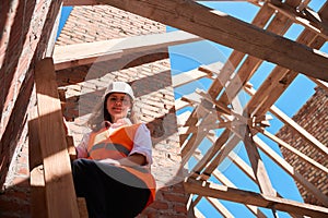 Woman project manager standing on ladder and looking at construction site