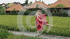 A woman with a projective figure dances alone on the rice field herself, takes her long skirt and skirt of a bright