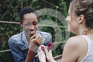 Woman proposing to her happy girlfriend outdoors photo