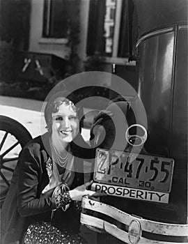 Woman with prosperity sign on car bumper