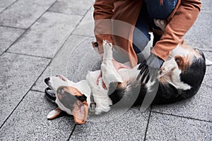 Woman with prosthesis arm scratching belly her dog