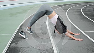 Woman with prosthetic leg doing yoga on racetrack. Lady stretching body