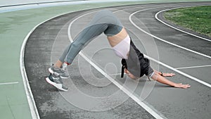 Woman with prosthetic leg doing yoga on racetrack. Lady stretching body