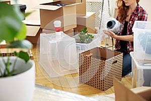 Woman protecting vase with foil while packing stuff into boxes after relocation