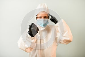 Woman in protective clothes shows fist and points to head