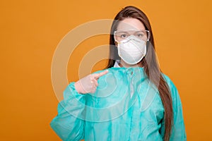 woman in protective equipment in medical mask on yellow background, coronavirus pandemic, look at the camera