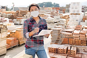 Woman in protective face mask controlling quantity of redbricks