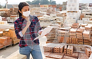 Woman in protective face mask controlling quantity of redbricks