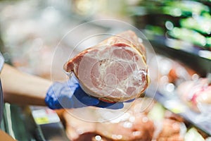 Woman in protective gloves buys meat in plastic packaging in a supermarket