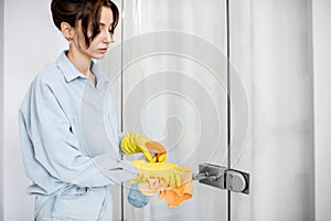 Woman cleaning door handle at home