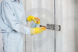 Woman cleaning door handle at home
