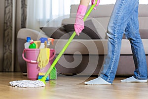 Woman in protective gloves using a wet-mop while cleaning floor