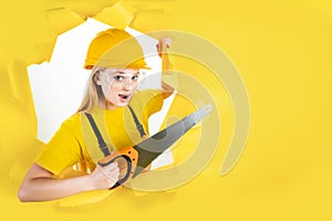 Woman in protective helmet is holding manual saw