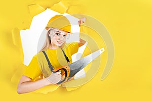 Woman in protective helmet is holding manual saw