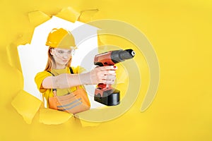 Woman in protective helmet is holding red screwdriver