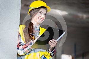 Woman in a protective helmet and a reflective vest conducts an inspection at a construction site