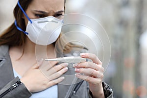 Woman with protective mask checking thermometer
