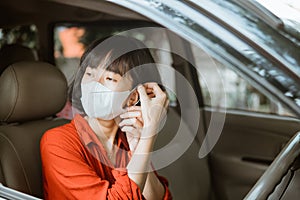 Woman in protective mask driving a car on road. Safe traveling.