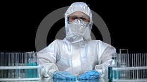 Woman in protective mask and glasses preparing for toxic work in laboratory