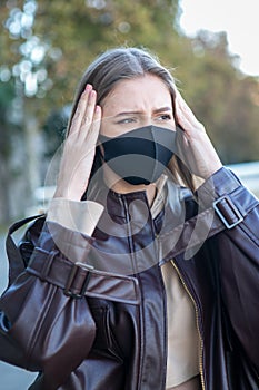 Woman with a protective mask having headache