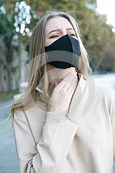 Woman with a protective mask having a sore throat