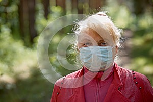 A woman in a protective mask walks in the Park, a walk in the fresh air after the quarantine, a precautionary measure