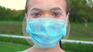 Woman in protective medical mask looking at camera.