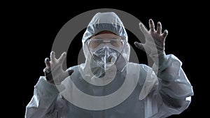 Woman in protective suit and mask, frighteningly raising hands, virus spreading photo