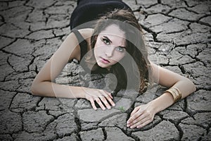 Woman protects a small sprout on a cracked desert soil