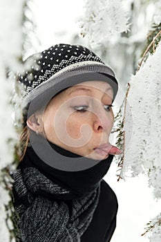 Woman protuding her tongue to the icy fir needles