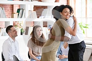 Woman psychologist addiction counsellor hugging supporting guy at group session