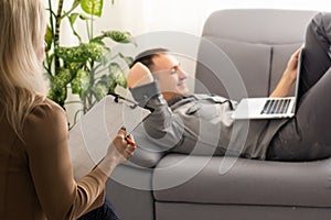 woman psychologist listening to the businessman client sitting during psychological session