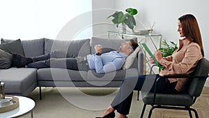 Woman psychologist sitting on chair listens patient at psychotherapy session