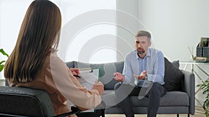 Woman psychologist taking notes on clipboard listen man at psychotherapy session